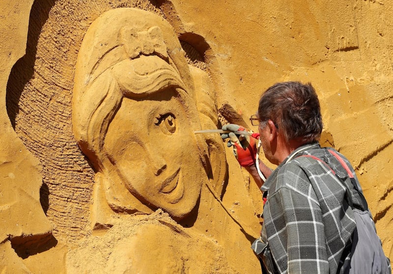 A sand carver works on a sculpture during the Sand Sculpture Festival. Yves Herman / Reuters