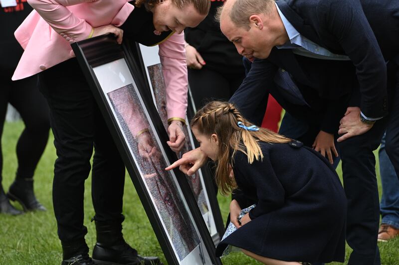 Princess Charlotte and her father the Duke of Cambridge look at a collage by artist Nathan Wyburn depicting the queen, at Cardiff Castle. PA