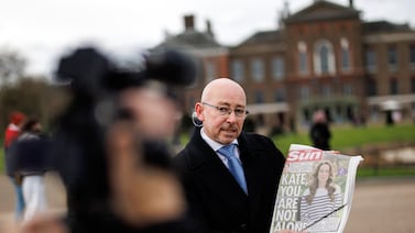 A TV reporter shows front the page of a British newspaper during a piece to camera outside Kensington Palace earlier this week. EPA