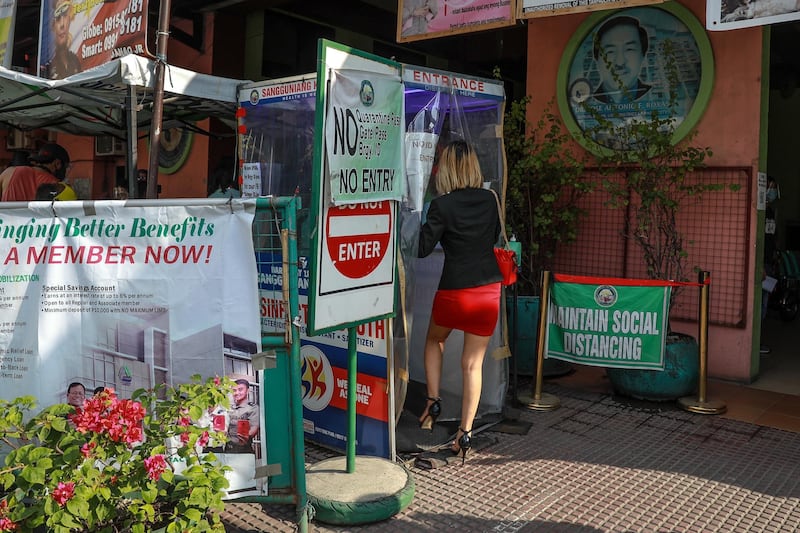 A woman walks through a disinfection booth while entering a town village in Pasay City, south of Manila, Philippines. EPA