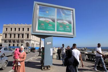 Algerians walk past posters promoting the vote for the upcoming referendum, Tuesday, Oct.13, 2020 in Algiers. A vote on a new constitution in Algeria will take place on Nov 1, 2020. AP