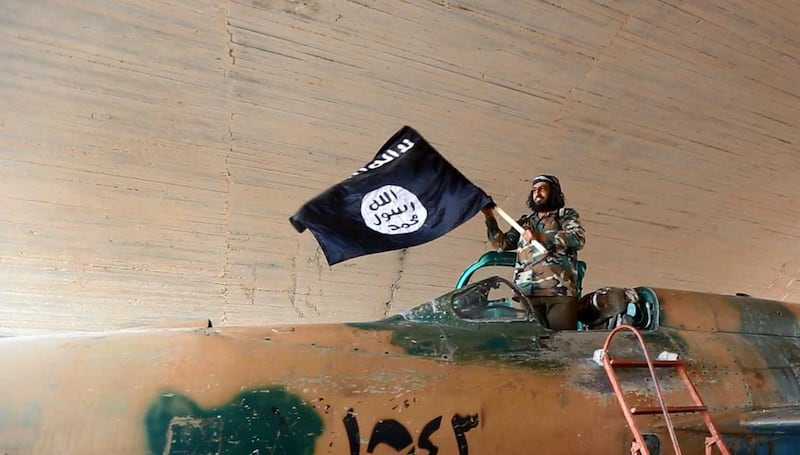 An ISIL member hoists a flag at a military airport in Raqqa, Syria.  AP /  Raqqa Media Centre of ISIL