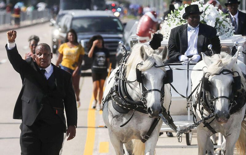 A man holds his hand up in solidarity as the body of George Floyd is brought by horse-drawn carriage in a funeral procession to Houston Memorial Gardens Cemetery for burial in Pearland, Texas. Getty