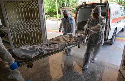 Employees transport the body of a COVID-19 victim to be cremated at the New Sonapur Hindu crematorium in the Gulf Emirate of Dubai on April 19, 2020. / AFP / GIUSEPPE CACACE
