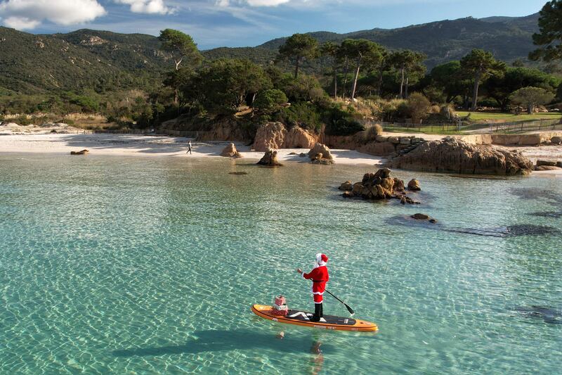A woman dressed as Santa Claus steering a paddleboard close to Mare e Sol beach on the French Mediterranean island of Corsica. AFP