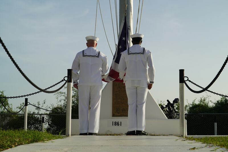 Two US Navy sailors stand at attention as they raise the American Flag at US Naval Station Guantanamo Bay.