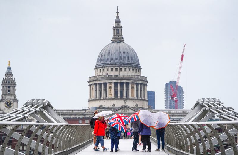 People caught in the rain on the Millennium Bridge in London. PA