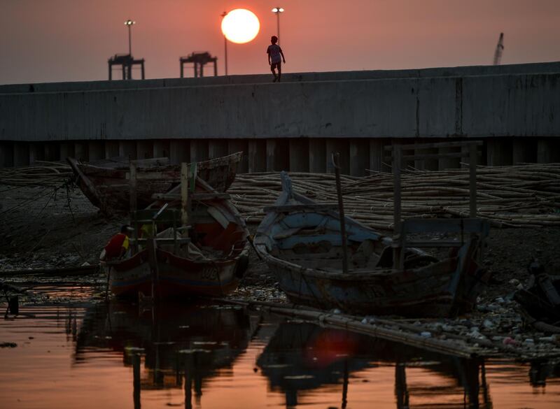 A boy walks on the top of a giant sea wall in northern Jakarta, during sunset. AFP