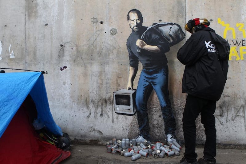 Banksy painted Apple founder Steve Jobs at the entrance of the Calais migrant camp in December 2015. AP