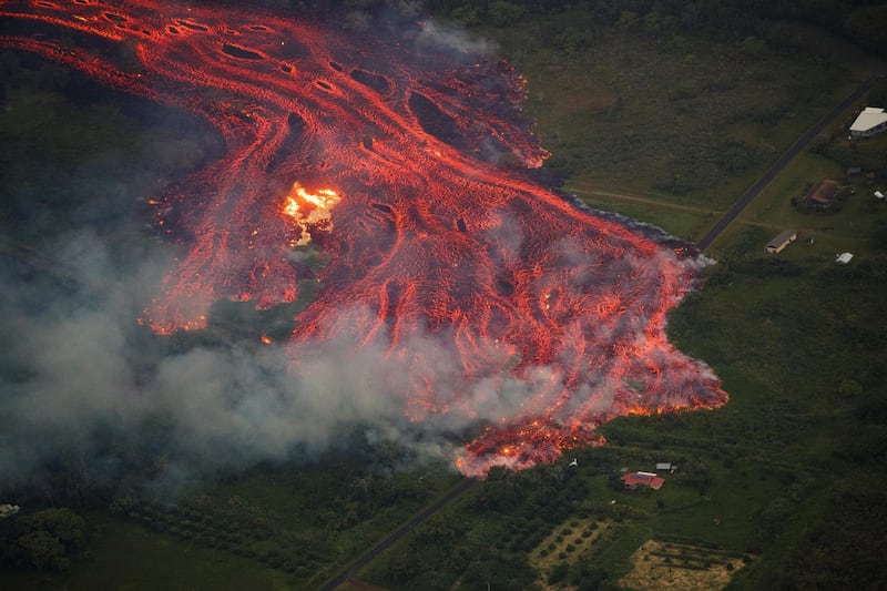 An aerial view of a massive flow of fast moving pahoehoe consuming everything in its path, as the flames from the remnants of one home burn (L), while it approaches another (R) in Pahoa, Hawaii. Bruce Omori / Paradise Helicopters / EPA