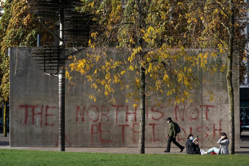A man walks past graffiti referring to coronavirus, in Manchester city centre. AP Photo