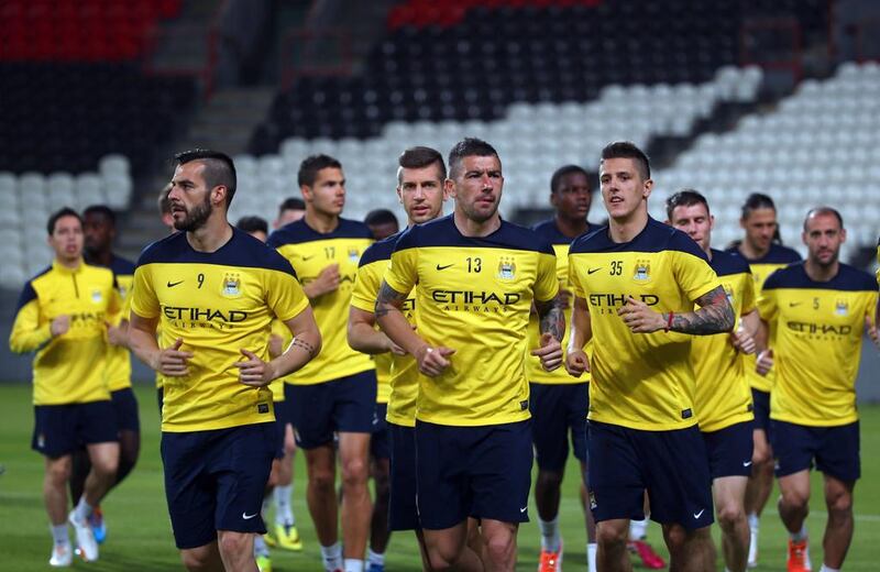 Alvaro Negredo, front left, Aleksandar Kolarov, front centre, and Stevan Jovetic, front right, lead a run during Manchester City's training session in Abu Dhabi on Wednesday. Marwan Naamani / AFP / May 14, 2014