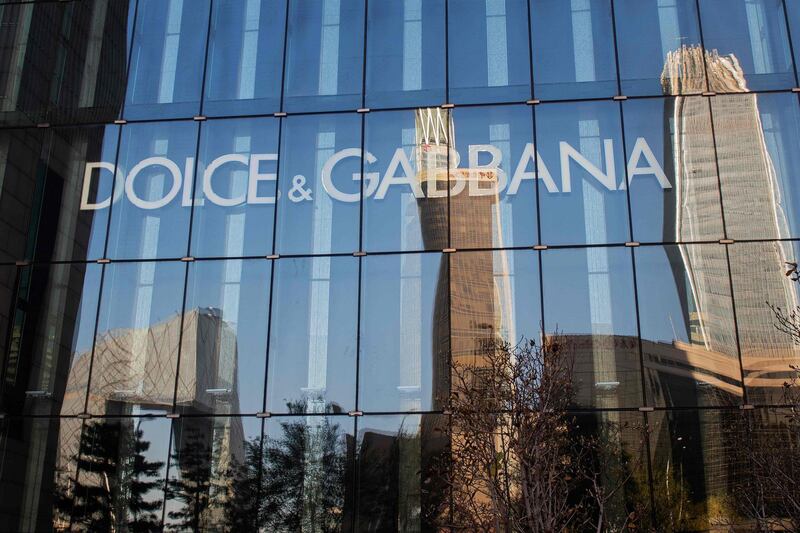 The Beijing skyline is reflected on the windows of a Dolce & Gabbana shop in Beijing on November 22, 2018.  Dolce & Gabbana cancelled a long-planned fashion show in Shanghai on November 21 after an outcry over racially offensive posts on its social media accounts, a setback for the company in the world's most important luxury market. / AFP / Nicolas ASFOURI
