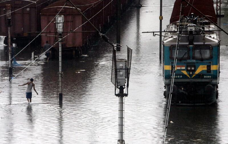 A man wades through a waterlogged railway track following heavy rains in Mumbai. AP Photo