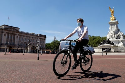 A man wearing a protective face mask cycles past Buckingham Palace, following the outbreak of the coronavirus disease (COVID-19), London, Britain, May 21, 2020. REUTERS/John Sibley