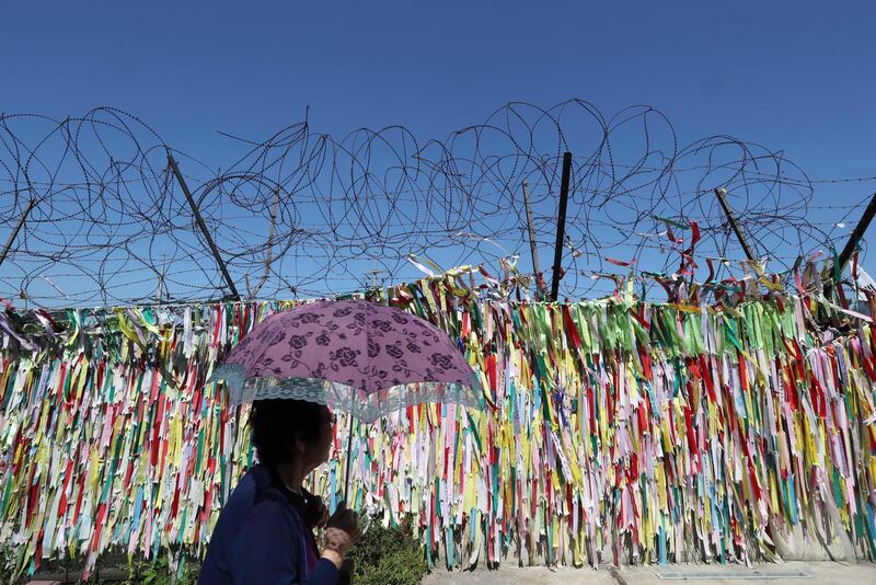 A visitor walks by a wire fence decorated with messages calling for the reunification of the two Koreas at the Imjingak Pavilion in Paju, South Korea. Lee Jin-man / AP Photo