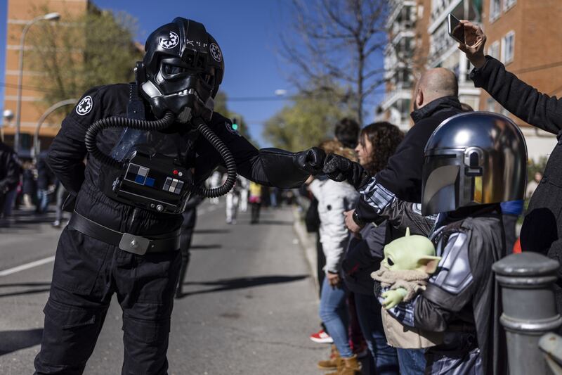 A Star Wars fan (L) disguised as a TIE fighter pilot greets a 'little Mandalorian' (R) during the Galaxy Day Parade in Madrid, Spain, 03 April 2022.  The event is organized by Star Wars fan clubs in support of social associations focused on mental illness and functional diversity.   EPA / Rodrigo Jimenez