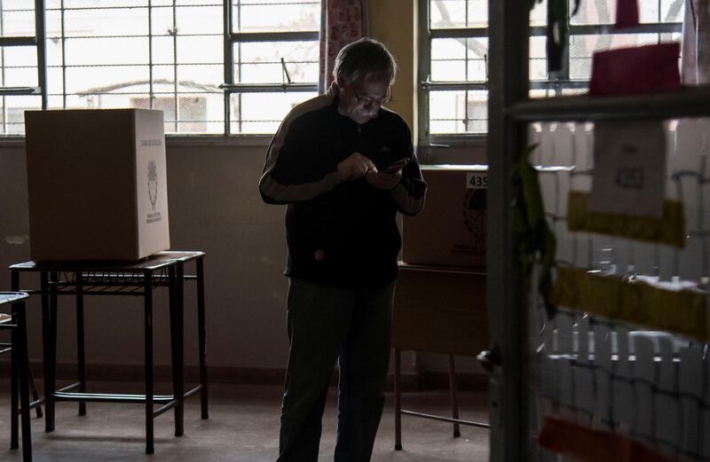 A man looks at his phone before casting a vote at a polling station during a national blackout, in Rosario, Santa Fe, Argentina.  Reuters