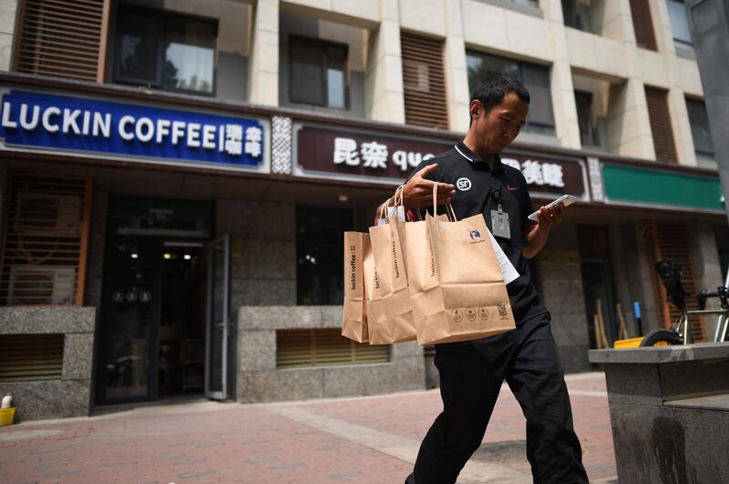 A deliveryman carrying bags of coffee walks out a Luckin Coffee in Beijing on August 2, 2018. 
Starbucks on August 2 announced a partnership with e-commerce giant Alibaba that will give the US coffee giant greater access to China's growing food-delivery market as it faces increased competition from local firms. / AFP PHOTO / WANG ZHAO