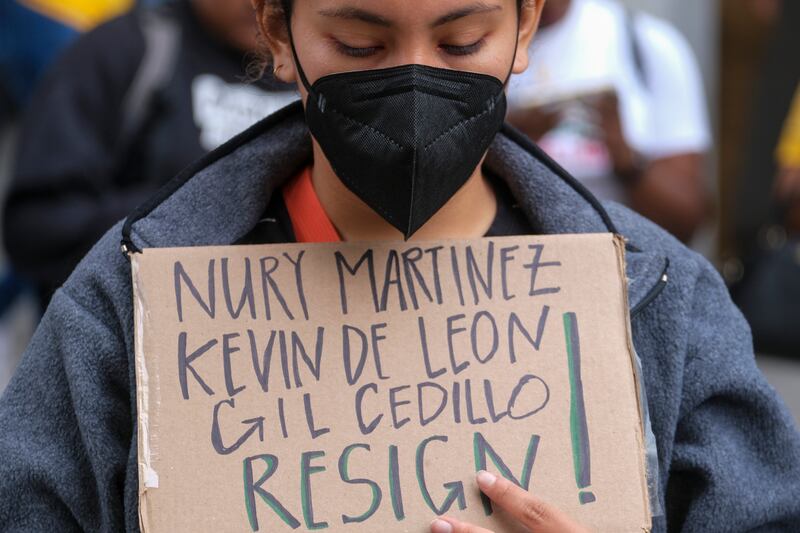 A protester holds a sign with the names of council members purportedly on the offensive recording. AP