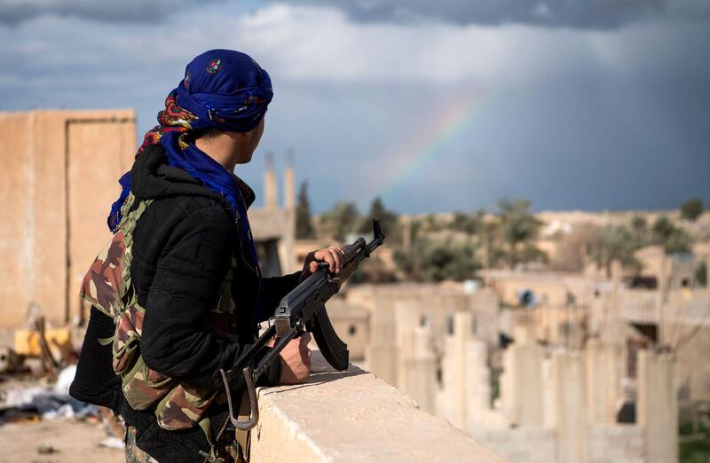 A member of the Syrian Democratic Forces stands guard on top of a building in the frontline village of Baghouz. AFP