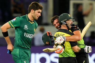 Australia's Marcus Stoinis and Matthew Wade (C) celebrate their victory as Pakistan's Shaheen Shah Afridi (L) watches at the end of the ICC men’s Twenty20 World Cup semi-final match between Australia and Pakistan at the Dubai International Cricket Stadium in Dubai on November 11, 2021.  (Photo by Aamir QURESHI  /  AFP)