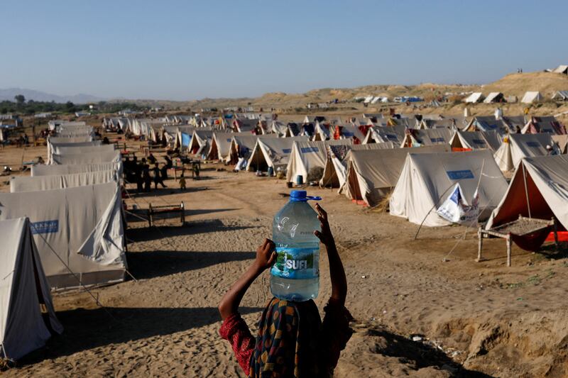 A girl carries a bottle filled with floodwater at a camp for displaced people in Sehwan, Pakistan. Reuters