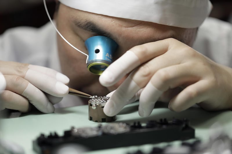 A watchmaker uses an eyepiece to assemble a mechanical movement of a Grand Seiko.