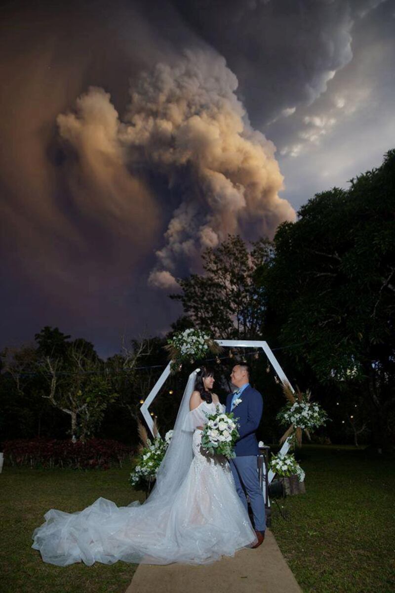 A couple attends their wedding ceremony as Taal Volcano sends out a column of ash in the background in Alfonso, Cavite, Philippines. Reuters