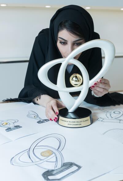 Emirati artist Ashwaq Abdulla examines closely the trophy she has designed for the tournament. Courtesy of Mubadala