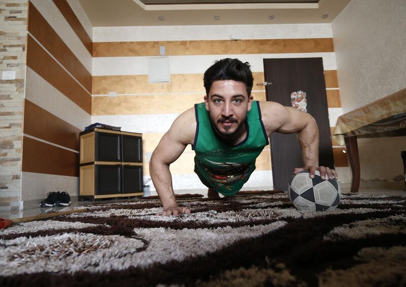 TOPSHOT - Ahmed Sawi, a Palestinian fitness and bodybuilding trainer, uses alternative tools during a training session at his home in Gaza City, amid concerns about the spread of coronavirus, on April 1, 2020. AFP