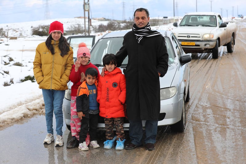 A family pose for a photo on a break from roaming the snow-covered roads.