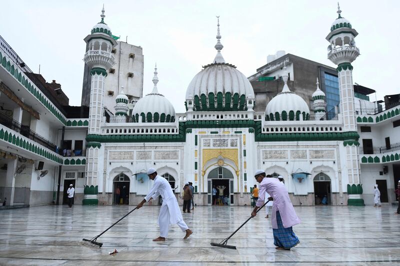 Mosque workers sweep out rain water before others arrive to offer morning prayers for Eid Al Adha at Jama Masjid Khairuddin in Amritsar, India.