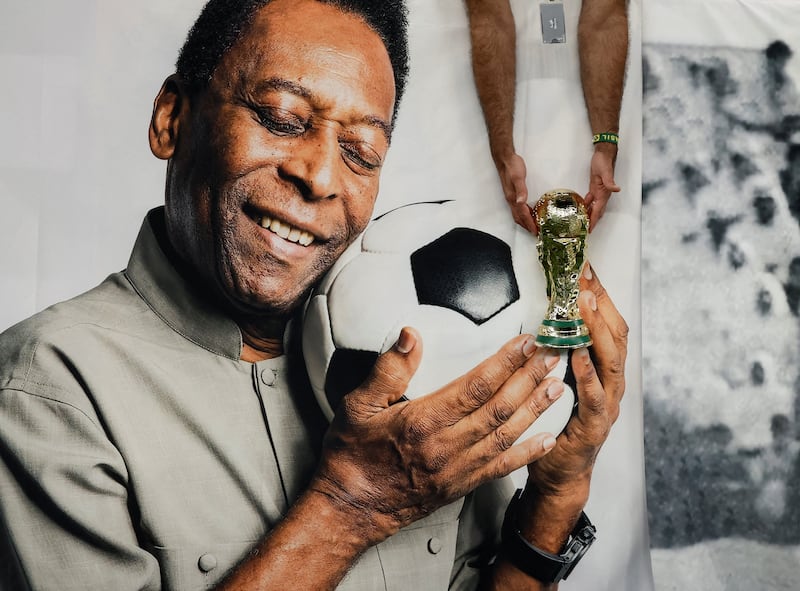 A football fan holds a replica World Cup trophy in front of a banner of former Brazil player Pele inside the Lusail Stadium in Qatar. Reuters 
