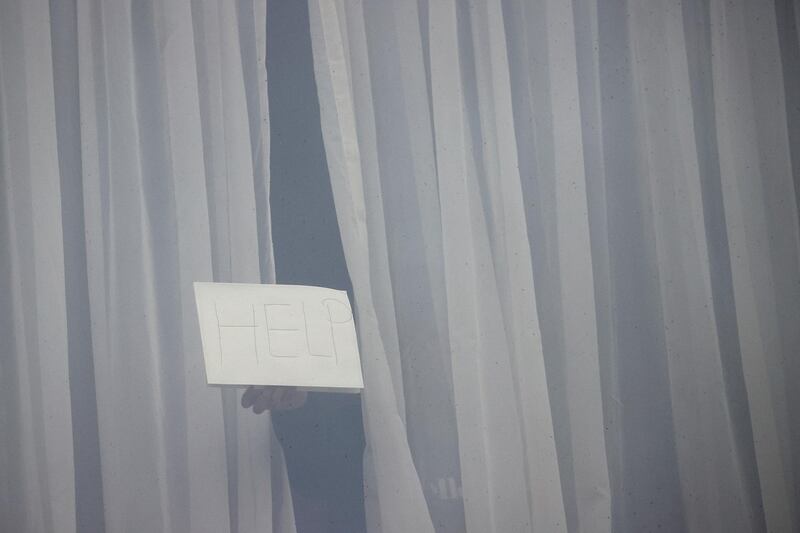 A person holds a sign from a window of the Radisson Blu Hotel at Heathrow Airport, as Britain introduces hotel quarantine programme for arrivals from a "red list" of 30 countries in London, Britain, February 16, 2021. Reuters