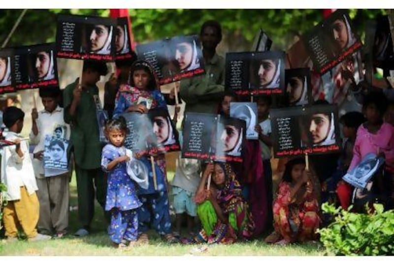 Pakistani flood affected victims carry photographs of child activist Malala Yousafzai to mark the "Malala Day" in Karachi.