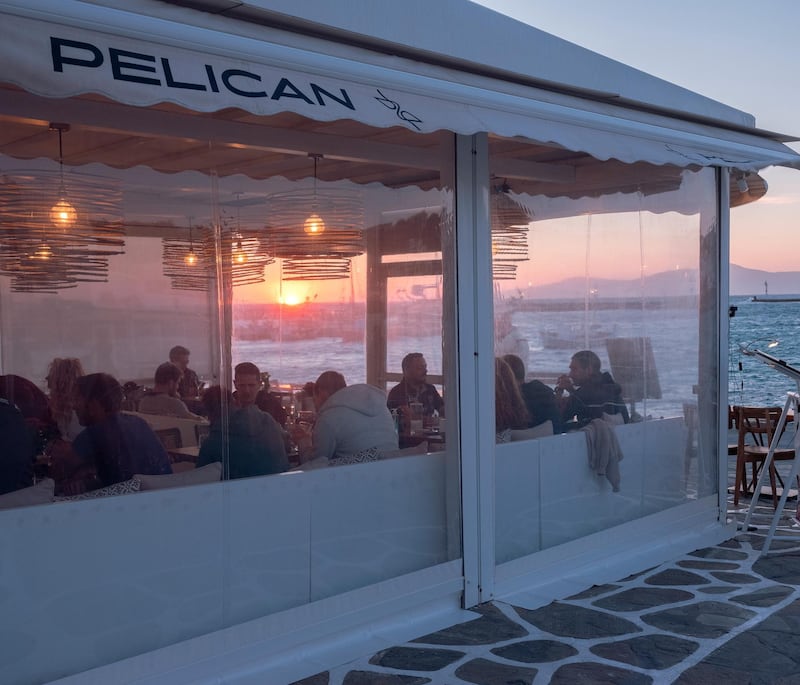 Customers dine at a recently reopened restaurant in the Old Port of Mykonos. Photographer: Loulou D'Aki/Bloomberg