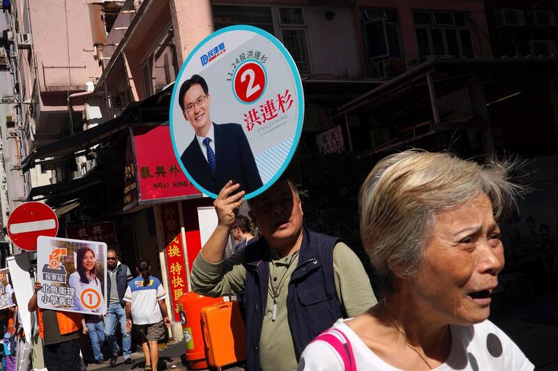 Supporters of pro-democracy and pro-government candidates campaign outside a polling centre. AP Photo