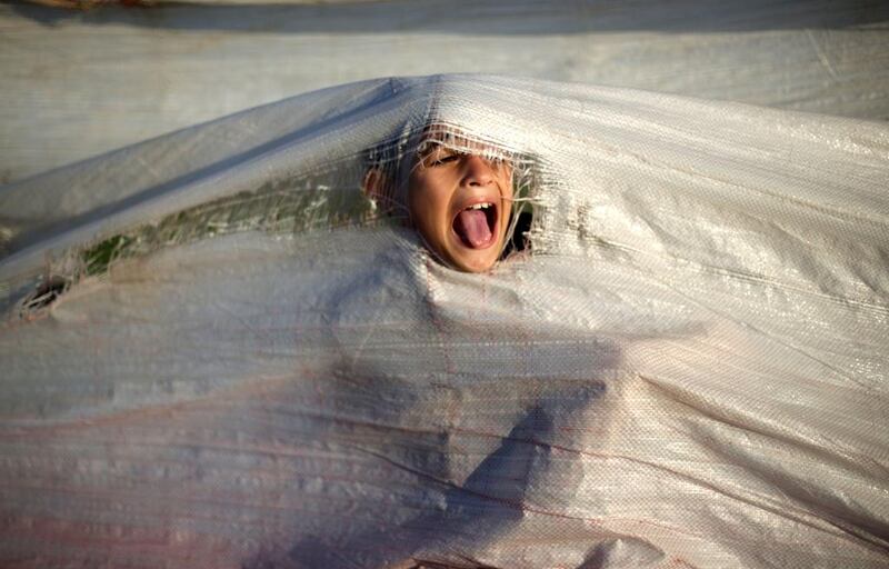 A Palestinian child plays under a tarp at the harbour in Gaza City. Mohammed Abed / AFP