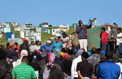 People hold a community meeting after building shacks on a piece of land belonging to the Louiesenhof Wine Estate on August 8, 2018, in Stellenbosch, which is at the centre of the South African wine-producing region. - Hundreds of shacks have been erected on the property, which is next to the Kayamandi informal settlement, despite people being evicted from the same land several months ago. (Photo by RODGER BOSCH / AFP)