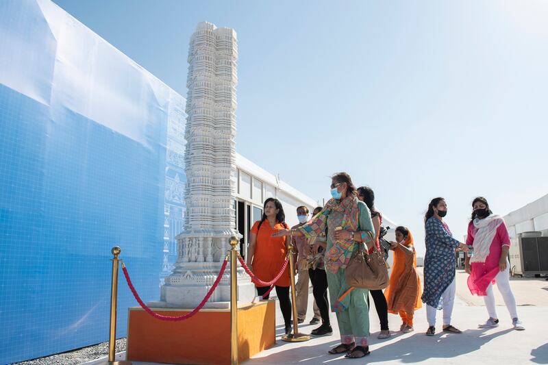 People offer prayers at a carved stone pillar.