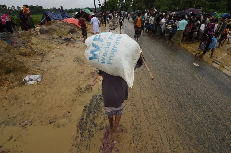(FILES) In this file photo taken on September 17, 2017 a Rohingya Muslim refugee carries a rice bag along a road near Balukhali refugee camp near the Bangladesh town of Gumdhum. The World Food Progamme (WPF) wins the 2020 Nobel Peace Prize, the Norwegian Nobel Committee has has announced on October 09, 2020.   / AFP / DOMINIQUE FAGET
