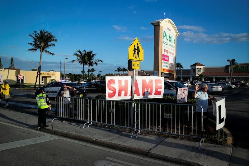 A protestor holds a sign as Donald Trump's motorcade heads to his Mar-a-Lago club, in West Palm Beach, Florida, April 18, 2019. Reuters
