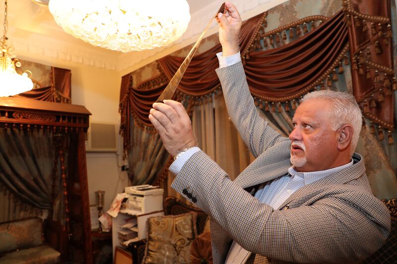 Shaukat holds up old negative films at his home in Dubai.