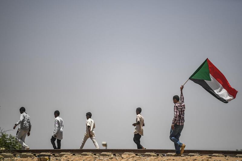 Sudanese protesters, walking on the railways, wave the national flag during a sit-in outside the army headquarters in the capital Khartoum on April 28, 2019.  AFP