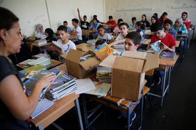 Palestinian refugee students receive new studying books inside their classroom, during the first day of a new school year, at one of the UNRWA schools, in Beirut, Lebanon, Monday, Sept. 3, 2018. The United Nations' Palestinian relief agency celebrated the start of the school year in Lebanon on Monday, managing to open its schools on schedule despite a multi-million dollar budget cut on the heels of U.S. President Donald Trump's decision to stop funding to the agency. (AP Photo/Hussein Malla)