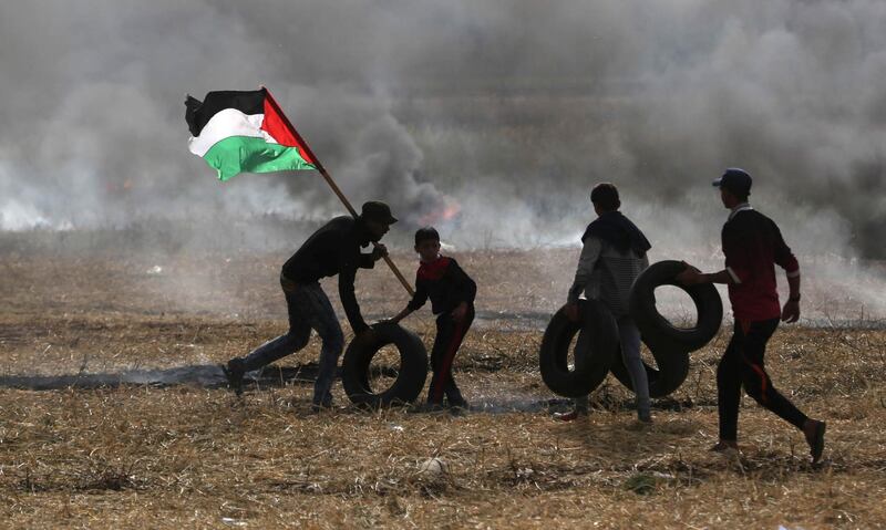 Palestinian protesters carry tyres to burn them during protests on the Israel-Gaza border. Ibraheem Abu Mustafa / Reuters