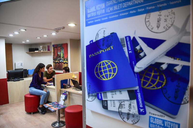 Turkish students inform themselves about US work and travel programs by an adviser at an education travel agency in Istanbul on October 11, 2017. 
Turkish students, business executives and travel operators have been left reeling by the country's dispute with the United States that has led both to suspend visas. / AFP PHOTO / OZAN KOSE