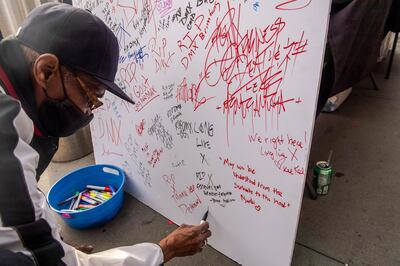 Ivey Bronson, 59, writes a note on a board for a "Celebration of Life Memorial" for rapper DMX at Barclays Center, Saturday, April. 24, 2021, in the Brooklyn borough of New York. DMX, whose birth name is Earl Simmons, died April 9 after suffering a "catastrophic cardiac arrest."  (AP Photo/Brittainy Newman)
