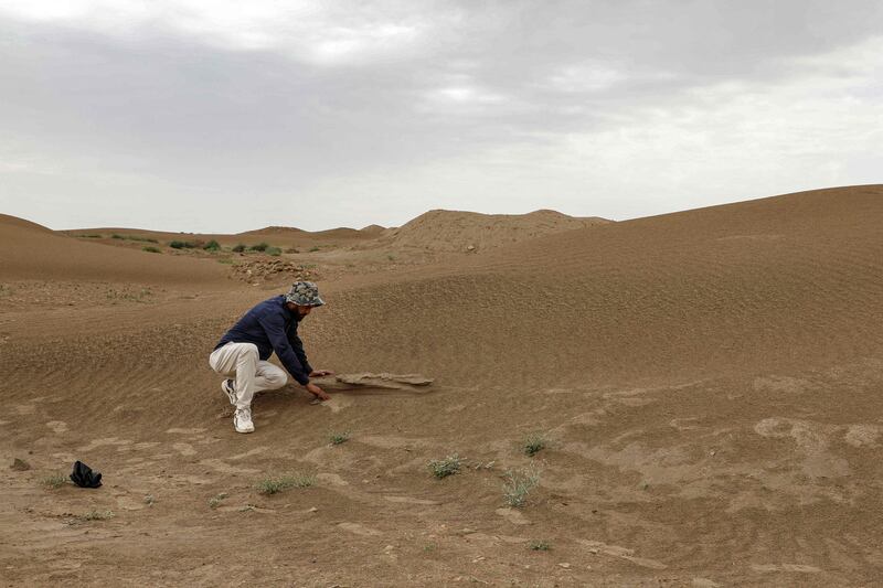 Mr Mansarawi searches for the remains of a building claimed by the desert sands 